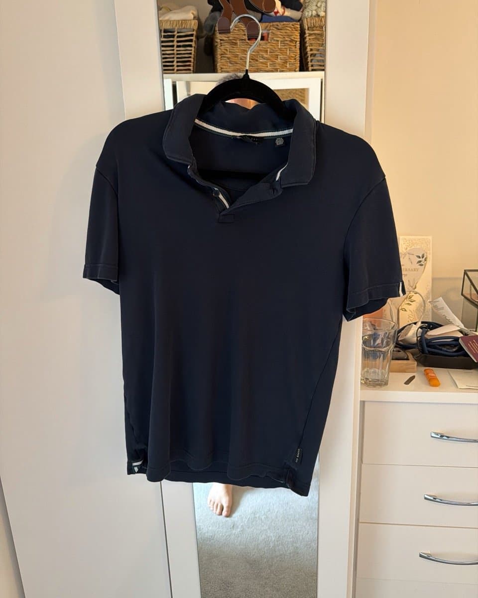 Rami's navy polo photographed on a bedroom mirror